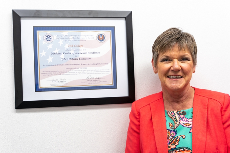 Jackie Armstrong next to framed certificate on wall